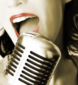 Image of a woman's mouth beind a microphone. Red lipstick and old-fashioned rockabilly mic